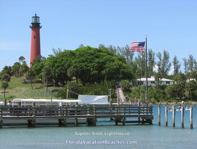 Jupiter Inlet Lighthouse from outside seating area of restaurant across inlet + Pelicans sitting on 5 old dock posts -  Florida